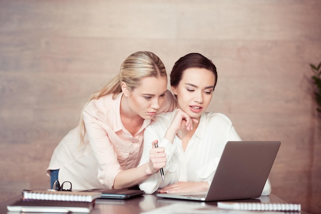 Giovani donne d'affari concentrate che guardano il portatile