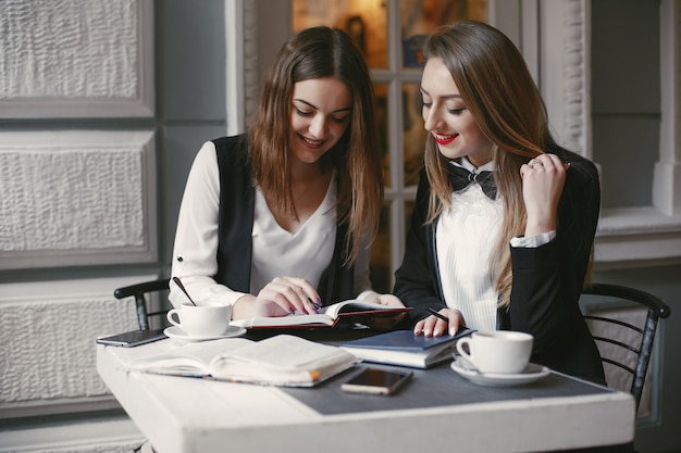 giovani donne di affari belle ed alla moda che si siedono in un caffè e nel funzionamento