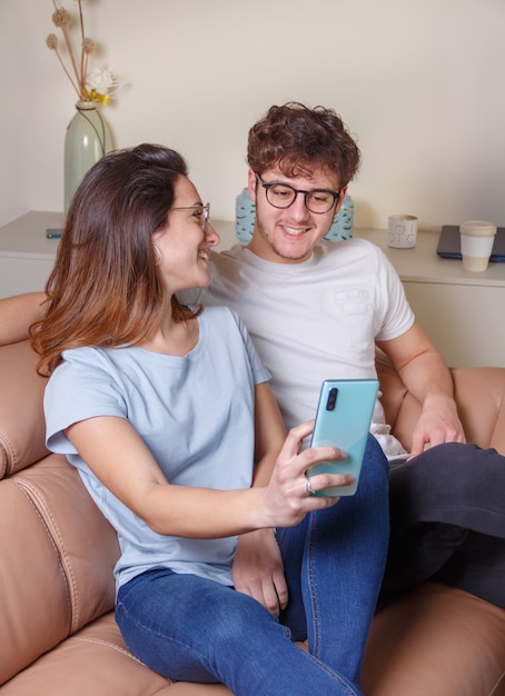 Giovani donne e uomini che si fanno selfie con il cellulare a casa