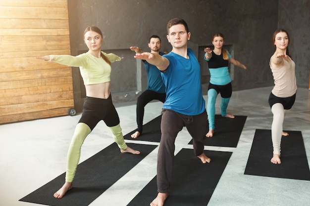 Giovani donne e uomini in classe di yoga, esercizi di stretching. Posa per il relax. Stile di vita sano nel fitness club, copia spazio