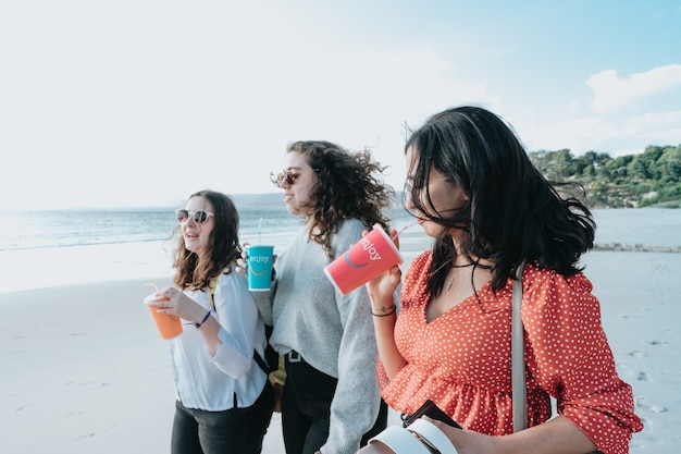 Giovani donne felici che ridono e sorridono in spiaggia in una giornata estiva, godendosi le vacanze, concetto di amicizia che si gode l'aria aperta