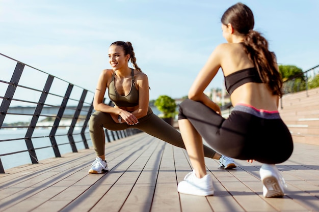 Giovani donne in abiti sportivi che si esercitano su una passeggiata sul fiume