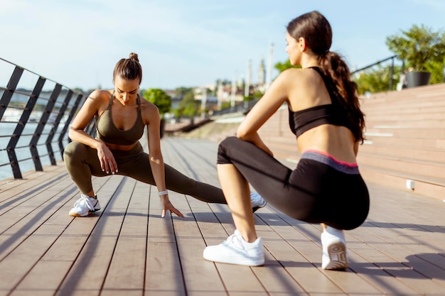 Giovani donne in abiti sportivi che si esercitano su una passeggiata sul fiume