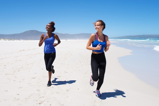 Giovani donne in buona salute che corrono lungo la spiaggia