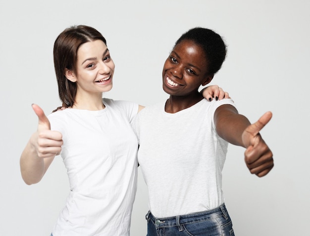 Giovani donne multirazziali in piedi insieme e sorridere alla telecamera isolata su sfondo bianco