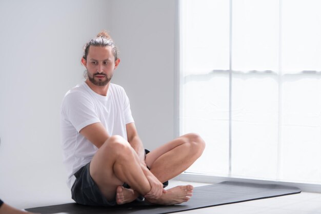 Giovani donne sedute a riposare su tappetini da yoga e bere acqua si guardano e sorridono