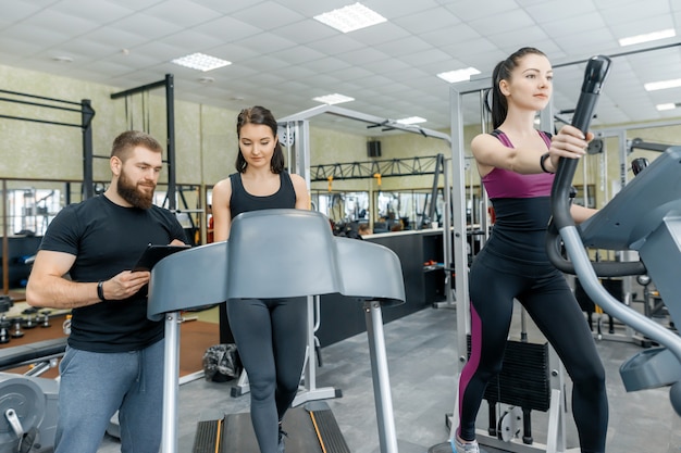 Giovani donne sorridenti di forma fisica con l'istruttore personale