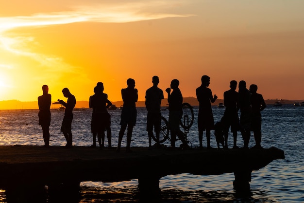 Giovani e silhouette si divertono insieme durante il tramonto in cima al ponte Crush nella città di Salvador Bahia