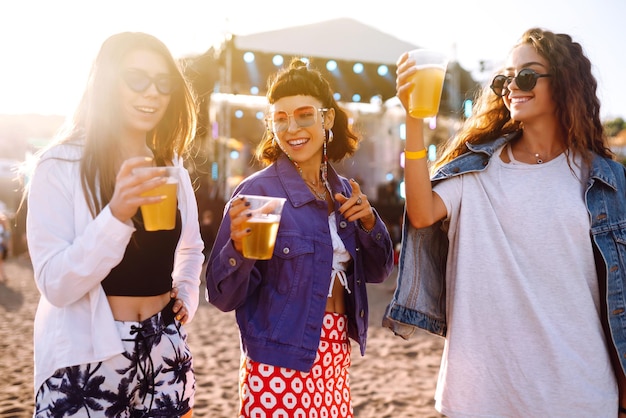 Giovani fidanzate che bevono birra divertendosi al festival musicale Celebrazione dell'amicizia Festa in spiaggia