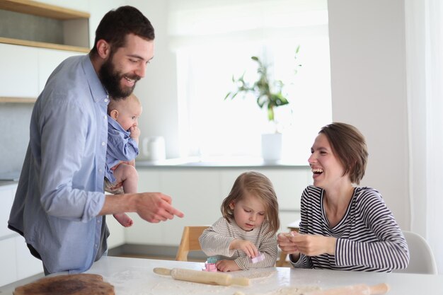 Giovani genitori che giocano con i bambini in cucina