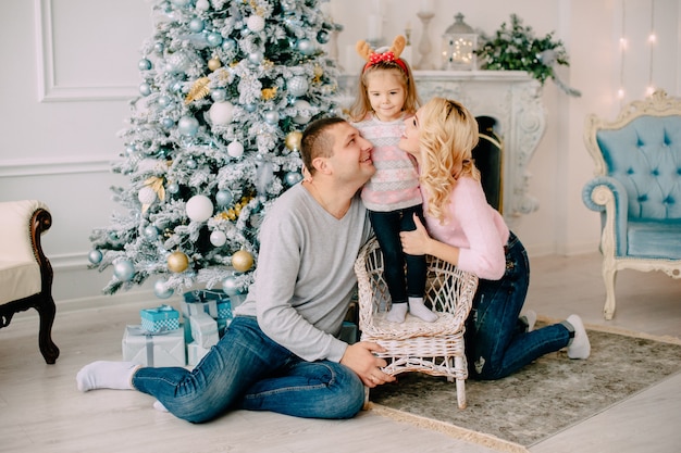 Giovani genitori che giocano con il bambino vicino all'albero di Natale