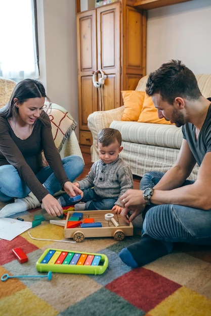 Giovani genitori che giocano con il loro figlio bambino un gioco in legno edificio nel soggiorno