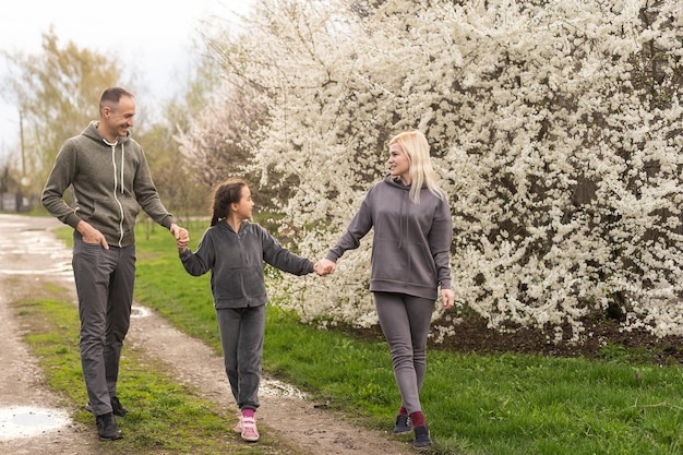 Giovani genitori con figlia che camminano fuori nella natura primaverile.