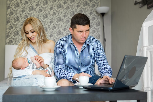 giovani genitori con un bambino a casa utilizzando un computer portatile