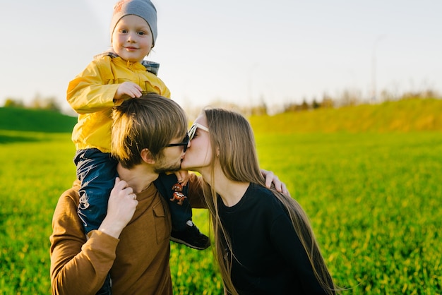 Giovani genitori con un giovane figlio che cammina su un campo al tramonto in estate. Concetto di famiglia