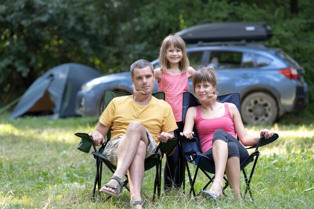 Giovani genitori di famiglia felici e la loro figlia che riposano insieme al campeggio in estate.