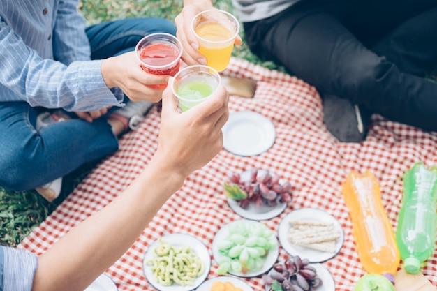 Giovani gruppi adolescenti che hanno divertimento picnic nel parco insieme.