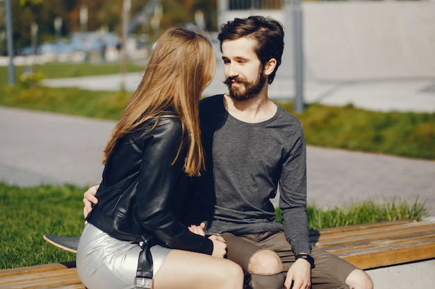 giovani hipsters seduti in un parco soleggiato estivo con uno skateboard nelle loro mani