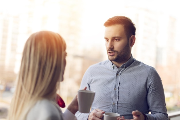 Giovani imprenditori di successo in pausa caffè e un po' di freschezza durante la discussione sul balcone di fronte all'ufficio.