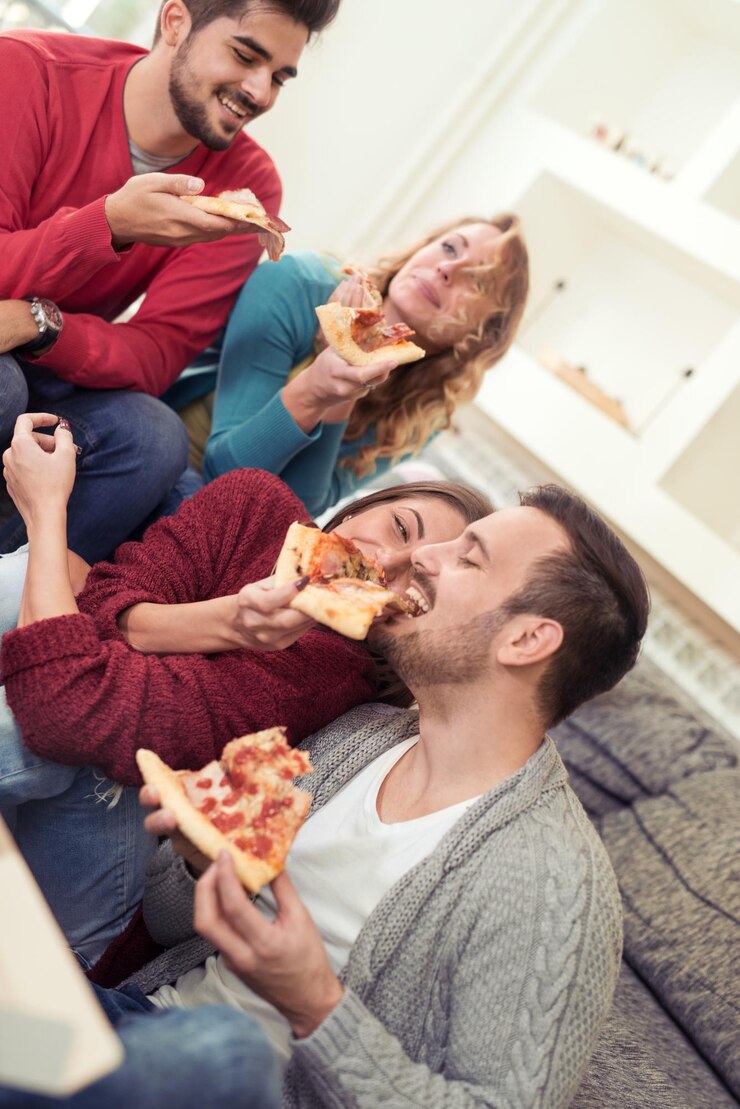 Giovani in abiti casual che mangiano pizza, parlano e ridono.