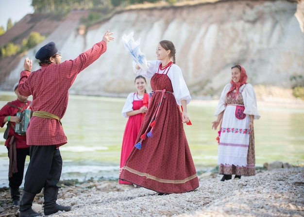 Giovani in costumi nazionali russi che ballano danze popolari suonando la fisarmonica