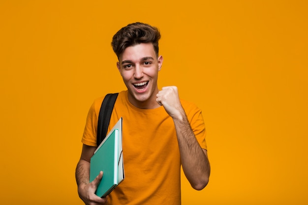 Giovani libri della tenuta dell'uomo dello studente che celebrano una vittoria