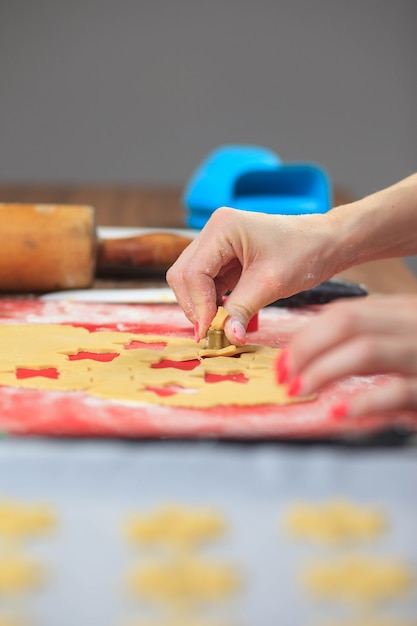 Giovani mani che tagliano la pasta dello zenzero alla cucina moderna