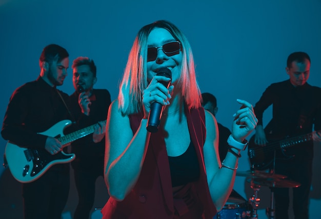 Giovani musicisti caucasici, band che si esibisce in luce al neon su sfondo blu studio