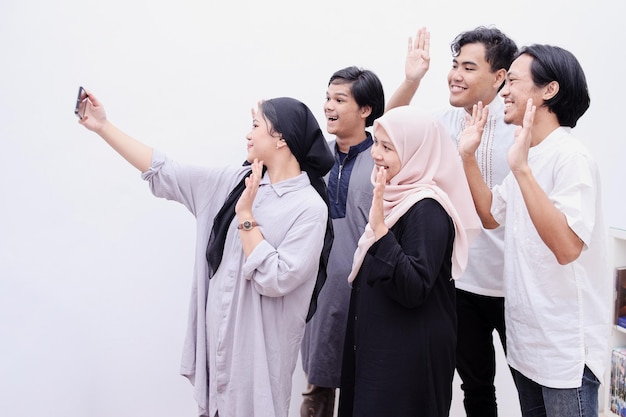 Giovani musulmani che prendono selfie o fanno videochiamate durante il momento di eid mubarak, isolati su briciolo