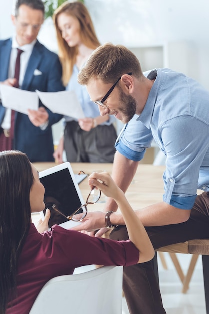 Giovani partner commerciali con tablet digitale che parlano nella sala conferenze