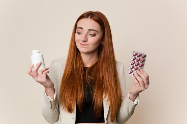 Giovani pillole rosse della tenuta della donna di affari dei capelli isolate