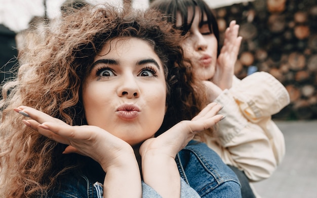 Giovani ragazze che giocano insieme facendo facce buffe mentre posa all'esterno