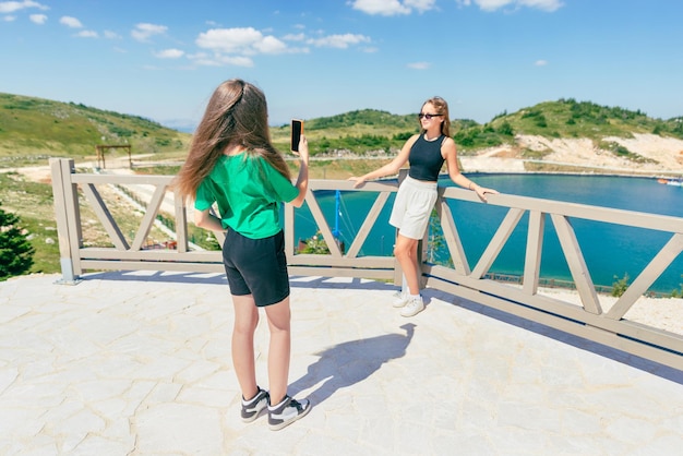 Giovani ragazze che scattano foto con il telefono a vicenda Ragazze adolescenti turistiche sulla montagna in riva al lago