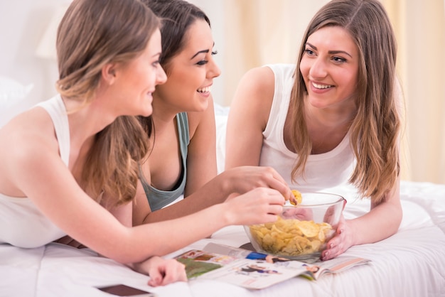 Giovani ragazze di bellezza in pigiama che leggono rivista.