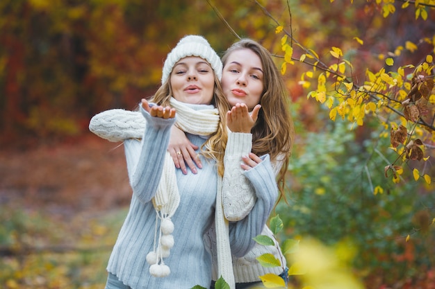 Giovani ragazze graziose divertendosi all'aperto in autunno. Amici allegri in autunno