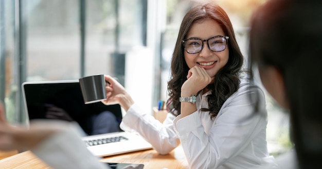 Giovani soci attraenti della donna di affari che discutono le idee di affari con felicità all'ufficio