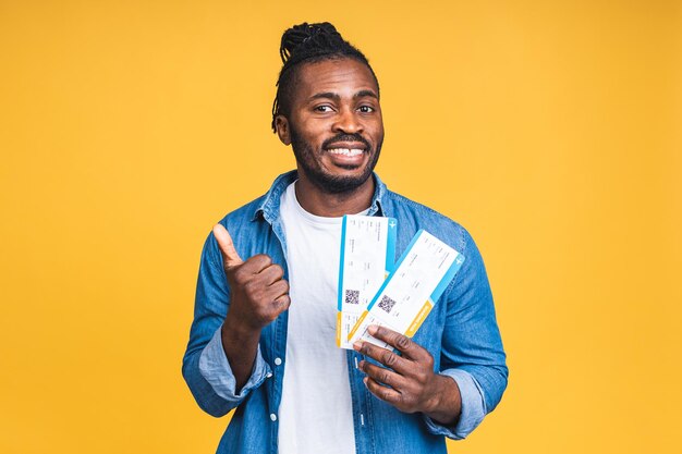 Giovani sorridenti African American Black Man Holding Boarding Pass biglietti isolati su sfondo giallo.