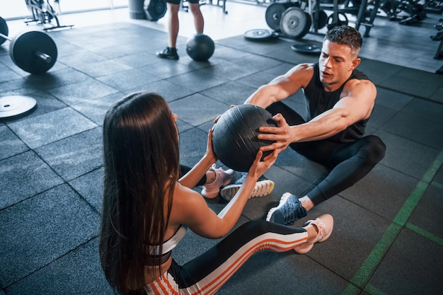 Giovani sportivi che fanno esercizi e tengono insieme la palla in palestra