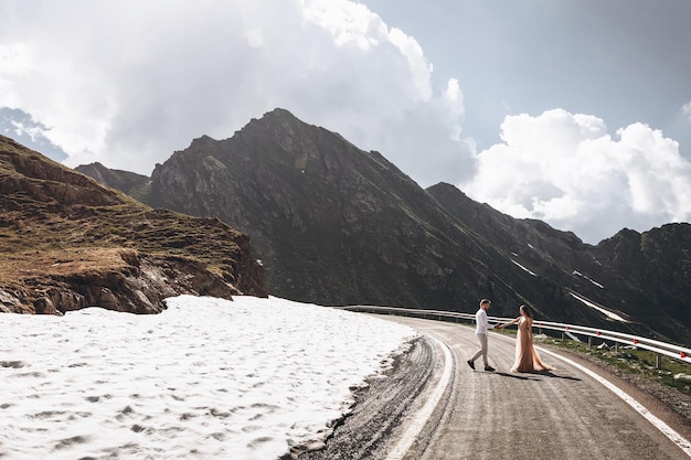 giovani sposi attraenti che camminano sulla lunga strada in montagna