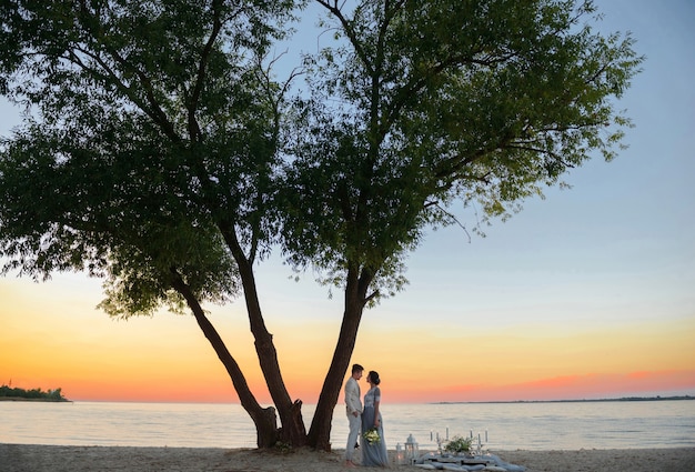 Giovani sposi vicino al mare sulla spiaggia al tramonto