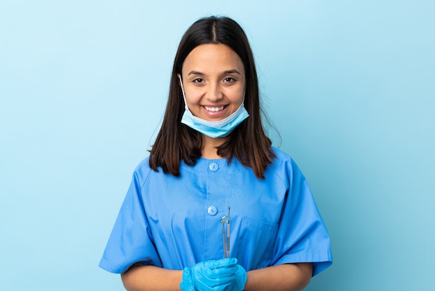 Giovani strumenti di tenuta castana della donna del dentista della corsa mista sopra la risata isolata del fondo