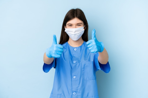 Giovani strumenti di tenuta della donna del dentista sopra la parete blu