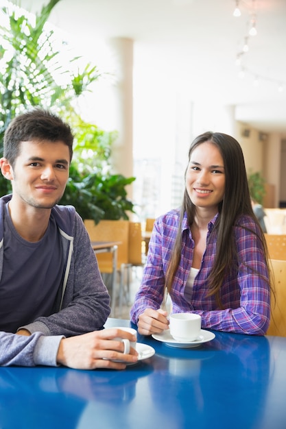 Giovani studenti che sorridono alla macchina fotografica in caffè