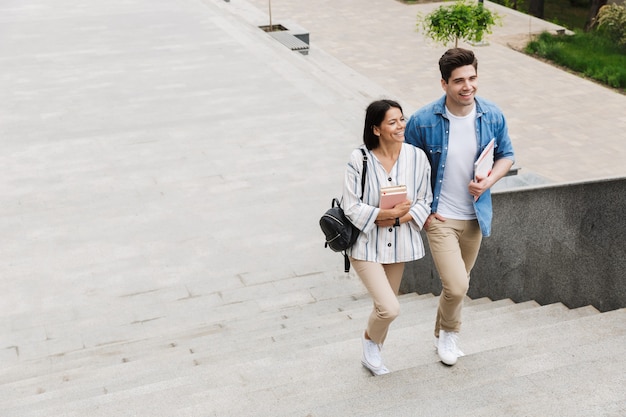 giovani studenti felici allegri incredibili coppie amorose all'aperto all'aperto camminando per gradini con i libri.