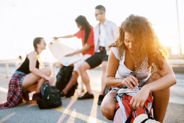 Giovani studenti in un tour turistico in una città facendo una pausa per cercare indicazioni stradali e riconfezionare