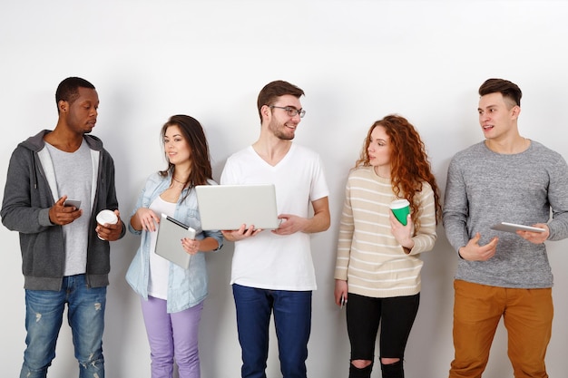 Giovani studenti multietnici con gadget, incontro al chiuso. Tecnologie educative moderne.