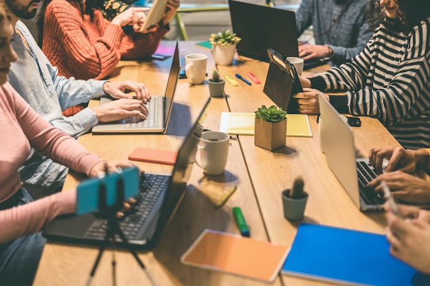 Giovani uomini d'affari che lavorano all'interno di un moderno ufficio di coworking - Focus sulle mani dell'uomo centrale