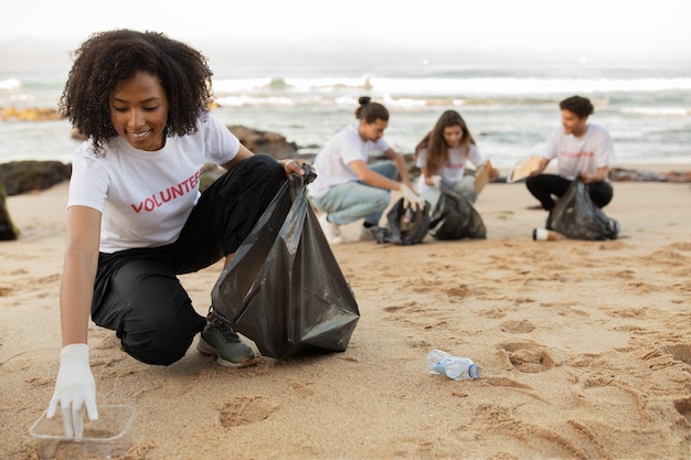 Giovani volontari multirazziali positivi in guanti di gomma e signora afroamericana con spazzatura