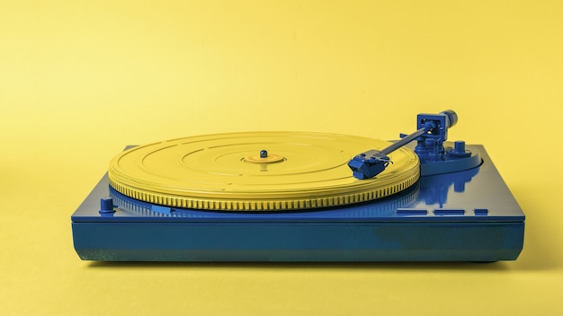 Giradischi in vinile vintage blu e giallo su sfondo giallo. Apparecchiature musicali retrò.