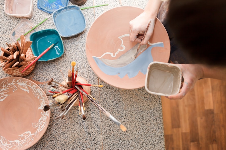 Girl draws with a brush on earthenware.